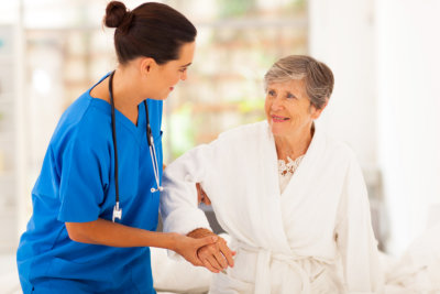 home caregiver helping senior woman getting up