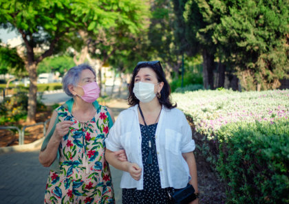 female caregiver and her patient walking outside the house