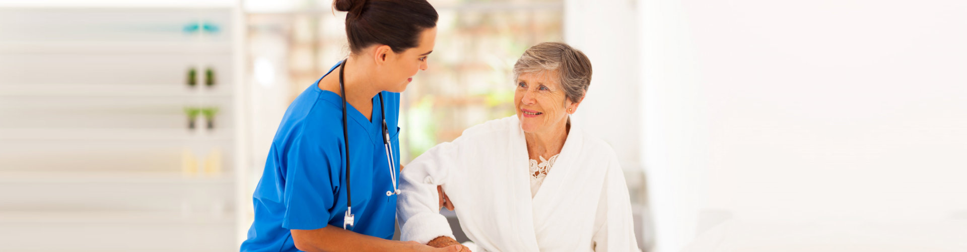 home caregiver helping senior woman getting up