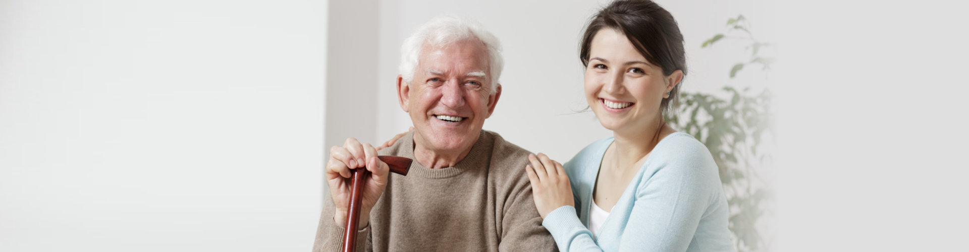 smiling old man holding a cane and smiling young woman